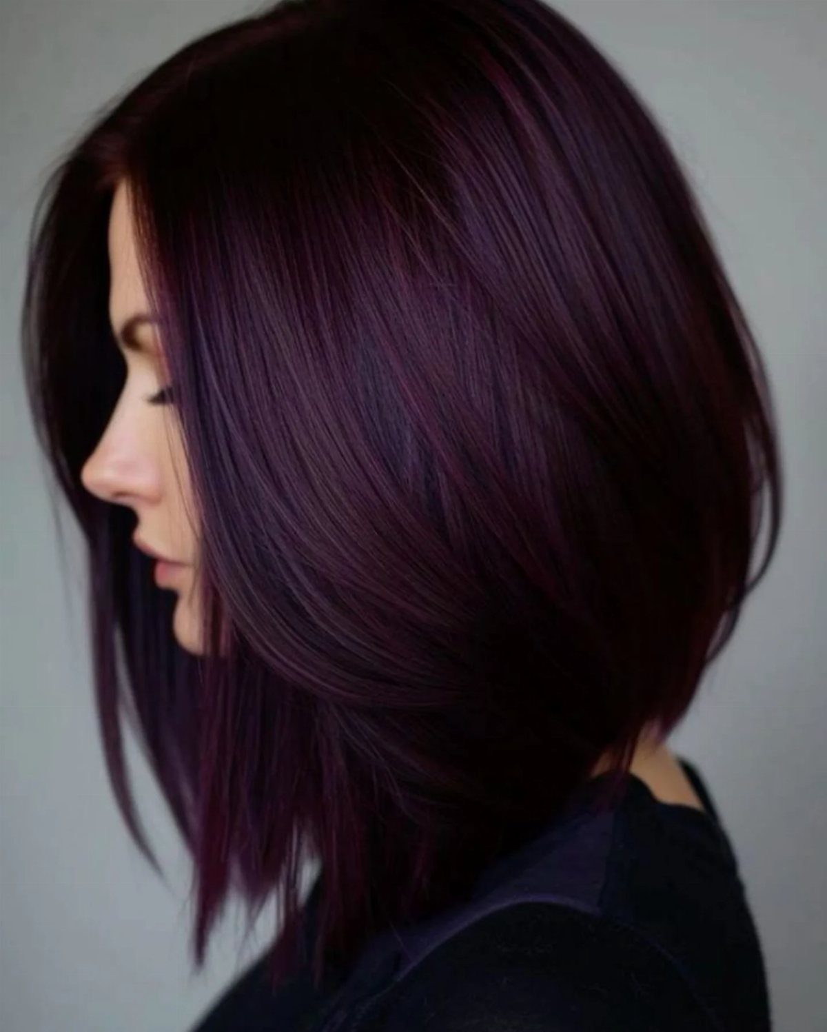 Woman with a sleek angled bob in a dark maroon purple hair color.