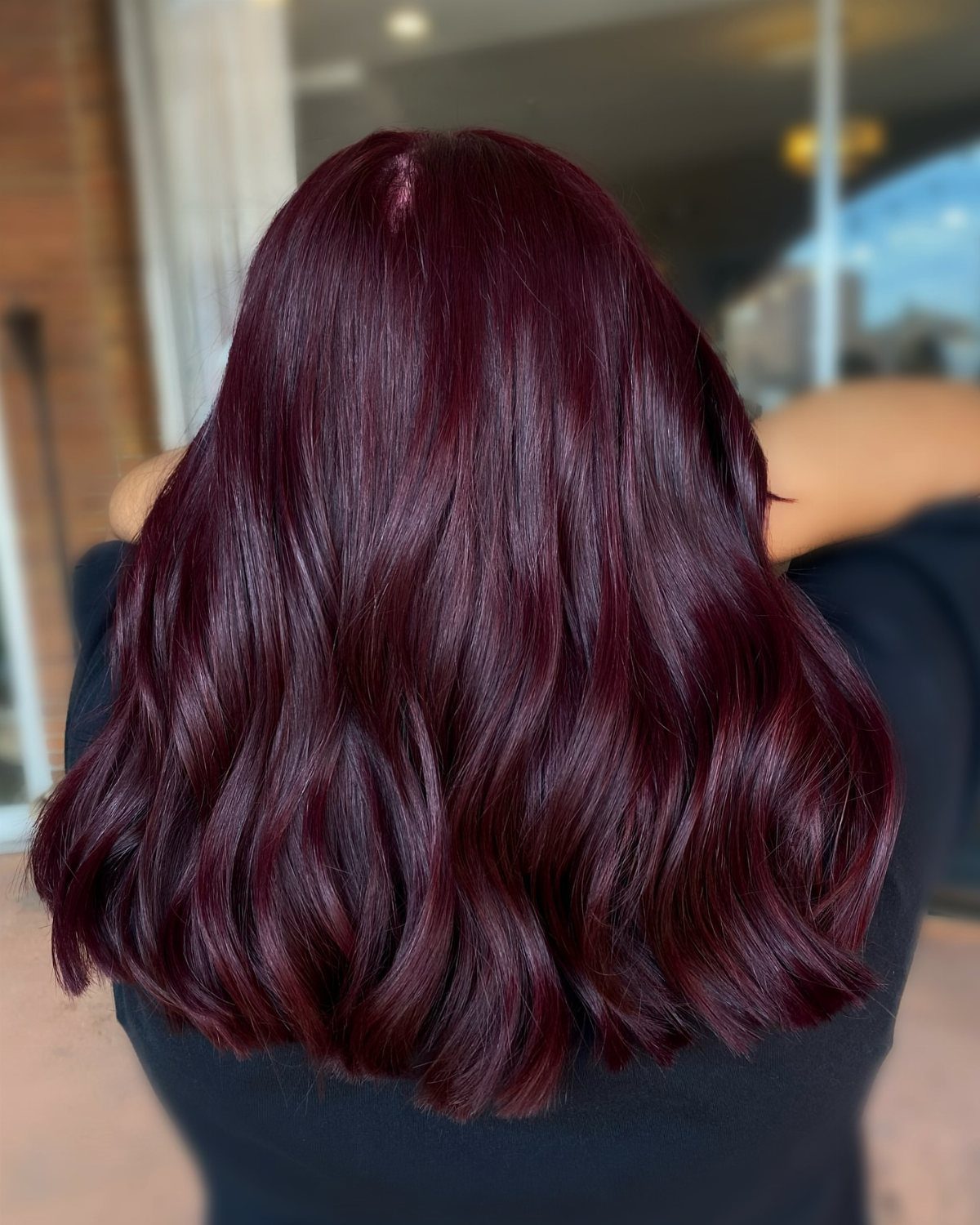 Long wavy dark maroon hair with a glossy finish seen from behind.