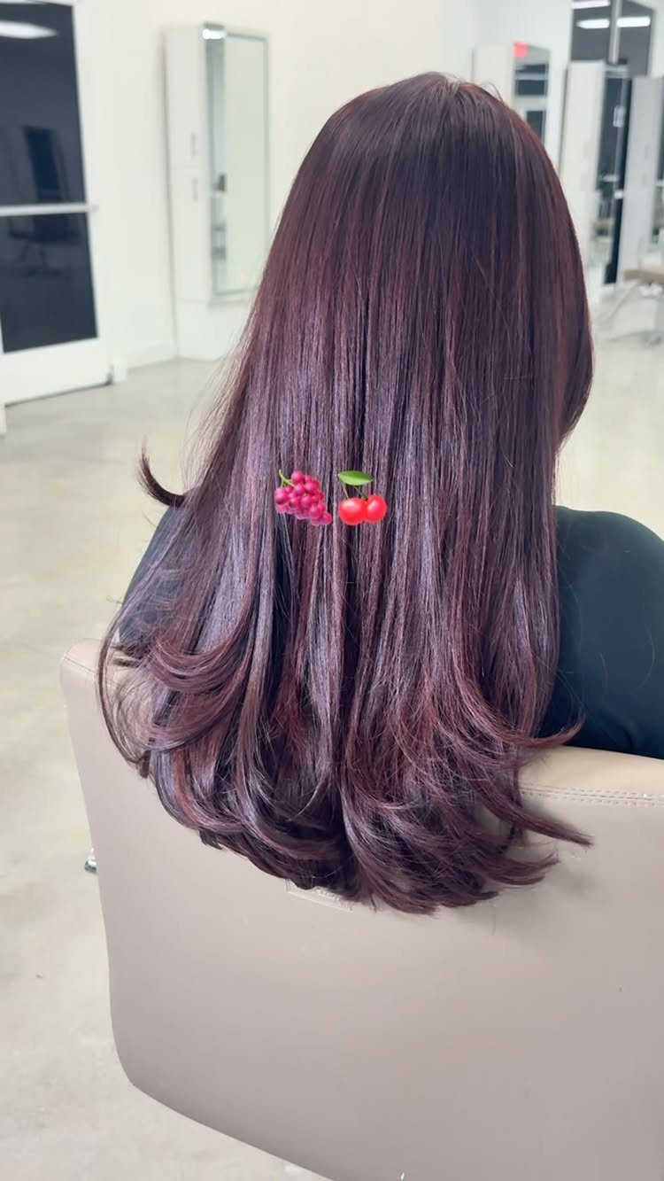 Long plum burgundy hair with curled ends and small red berry hair clips.