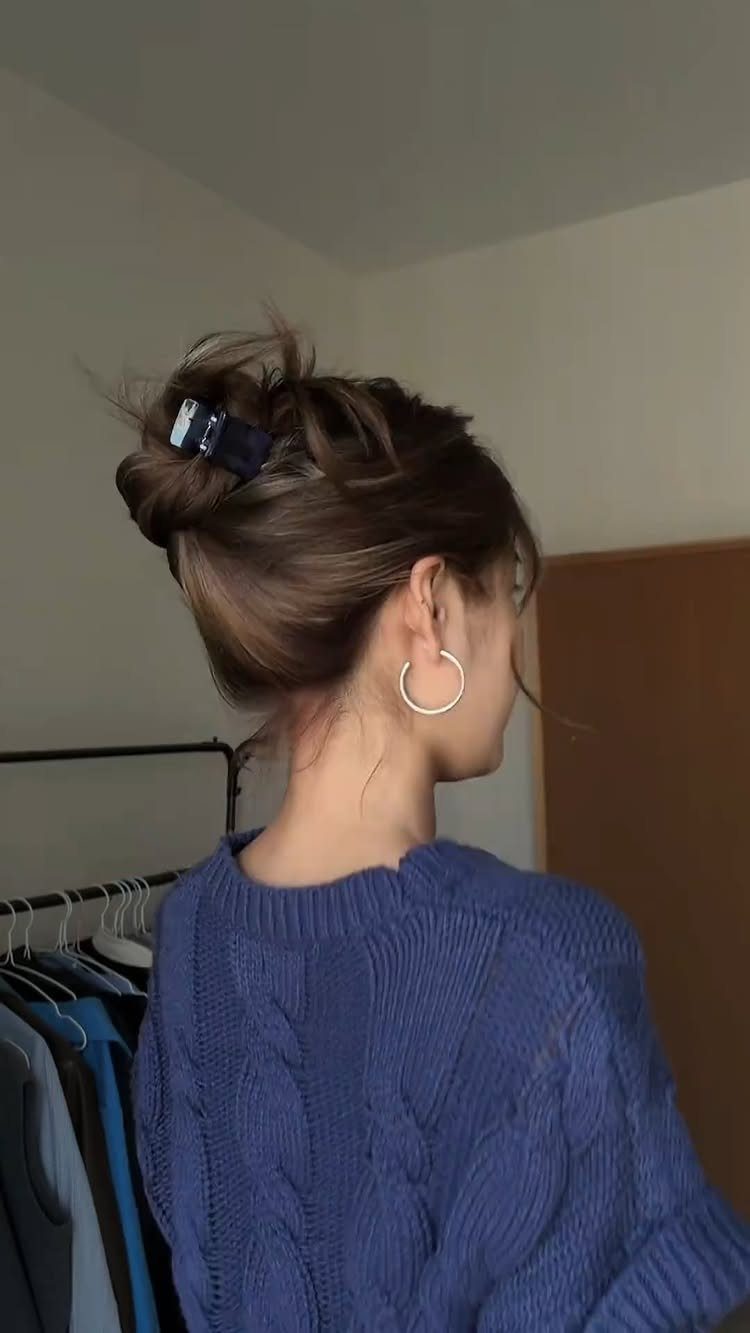 16 Easy Hair Styles for Beginners to Try at Home 3 Woman with brown hair in a messy bun secured by a blue claw clip