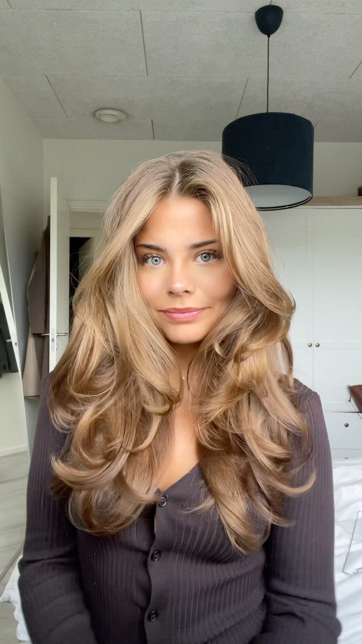 Fall Hair Dos with 15 Ideas from Burnt Copper to Claw Clips 11 Woman with long blonde layered hair styled in voluminous 90s waves.