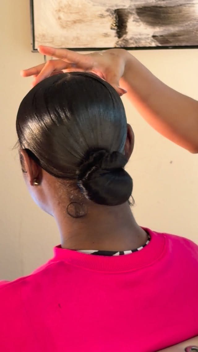 Fall Hair Dos with 15 Ideas from Burnt Copper to Claw Clips 4 Sleek low bun hairstyle on a person wearing a bright pink shirt.