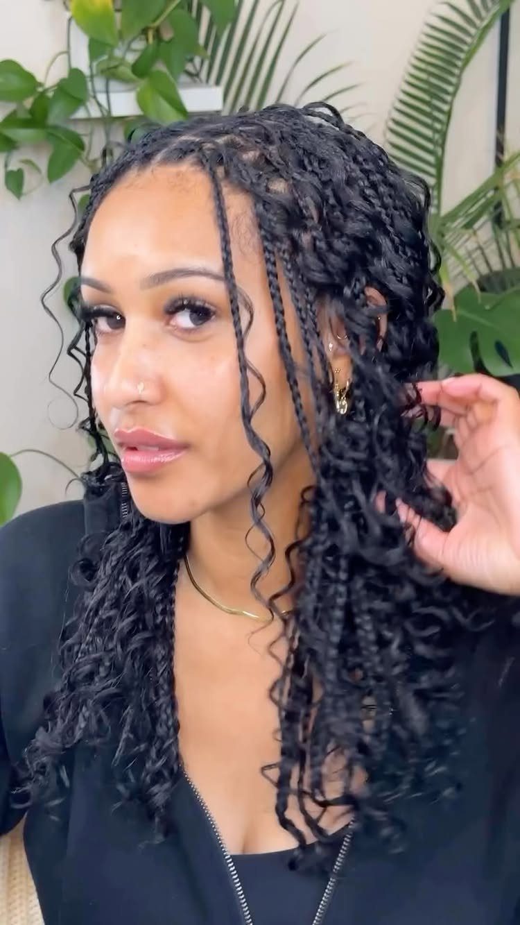 Woman with long black boho box braids and curly loose strands among plants