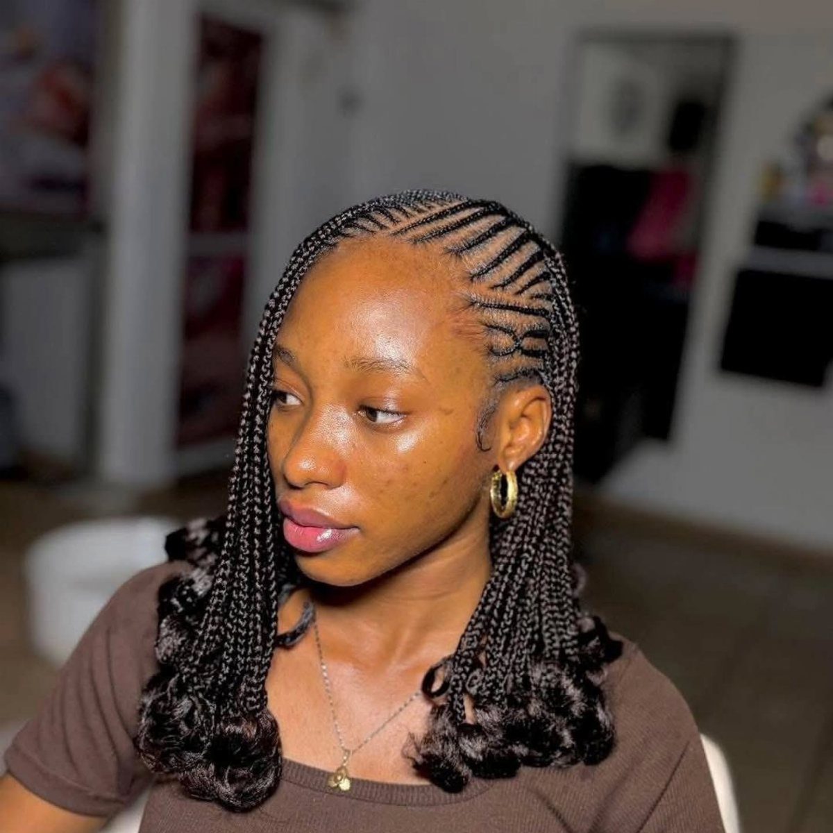 Woman with feed-in cornrows and shoulder-length braided curls in a bob style.