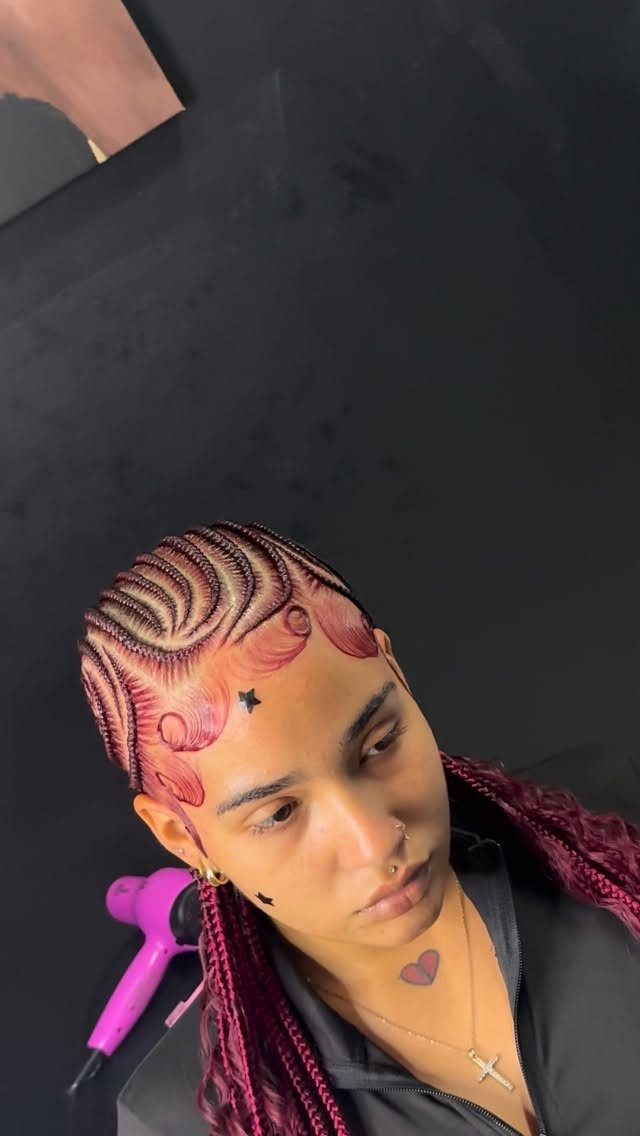 Woman with curved reddish-brown feed-in braids and long braids against dark background