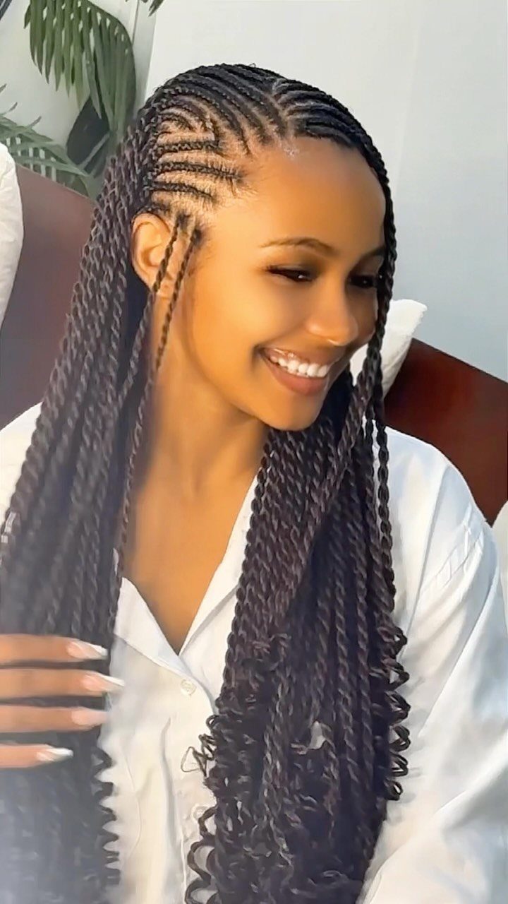 Woman with long dark goddess braids featuring cornrows and curly ends smiling.