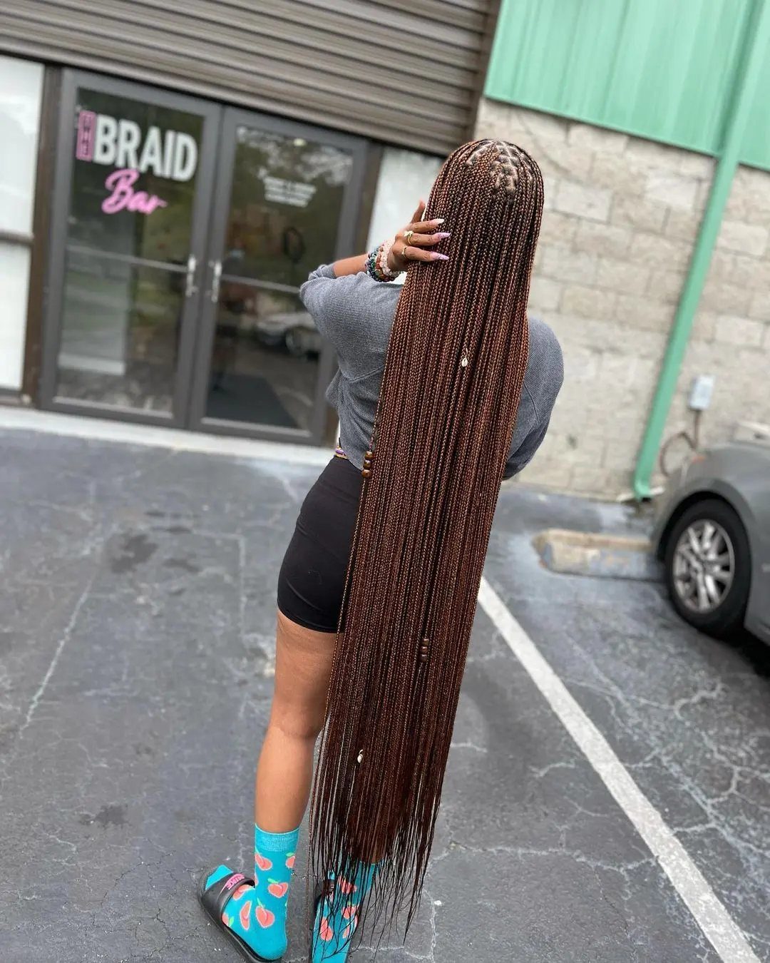 Woman from behind with very long, thin brown braids reaching her lower legs.