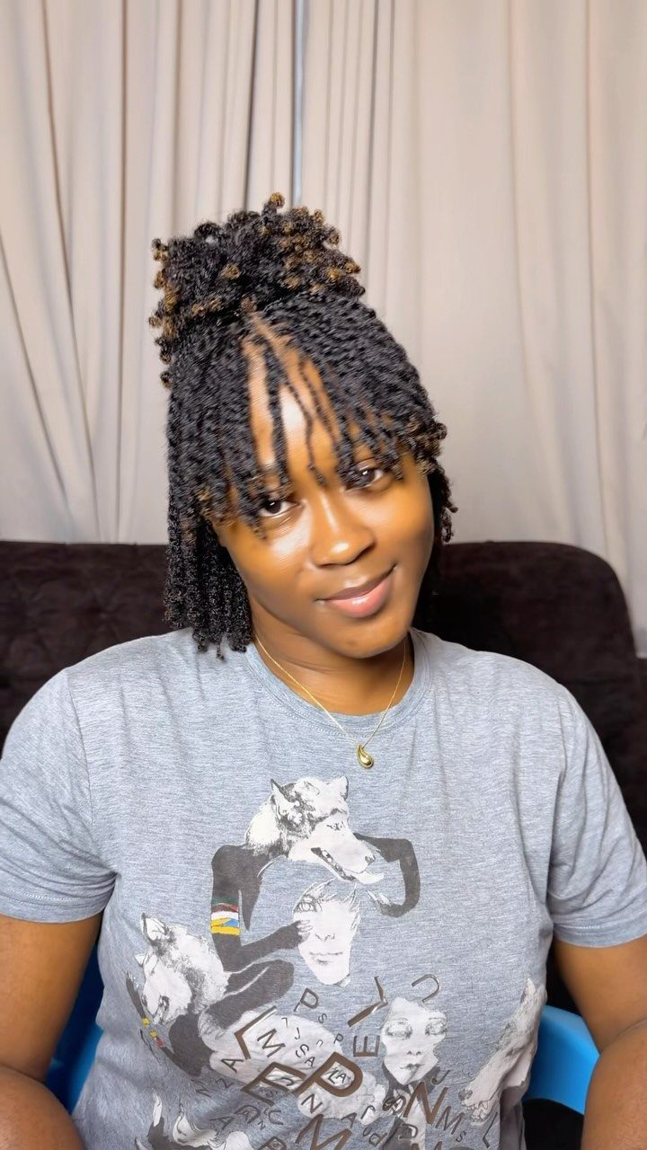 Woman with two-strand twists styled in a high bun and loose strands.