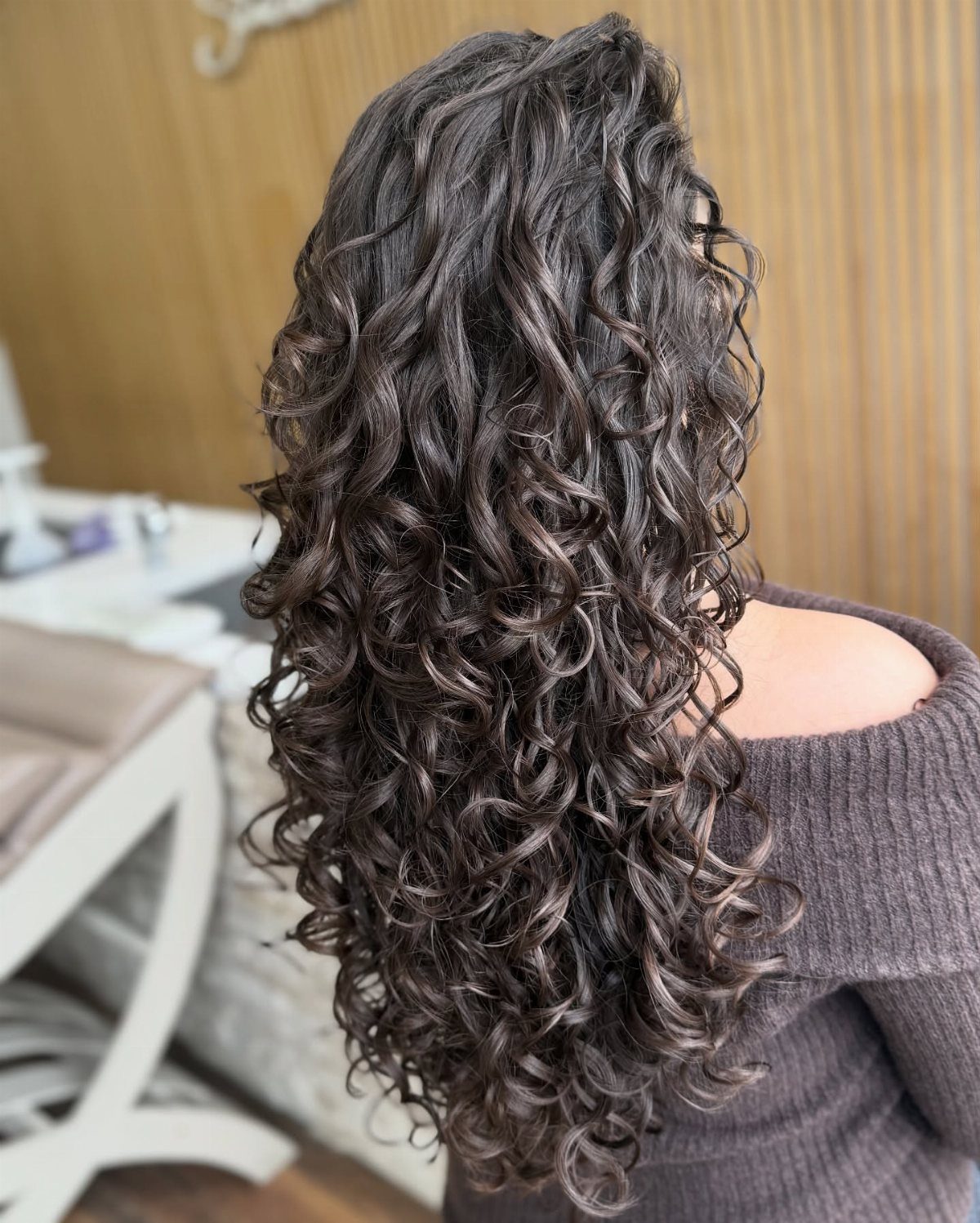 12 Good Hairstyles for Curly Hair, From Bangs to Braids 4 Long dark brown curly hair with layers cascading down a person's back