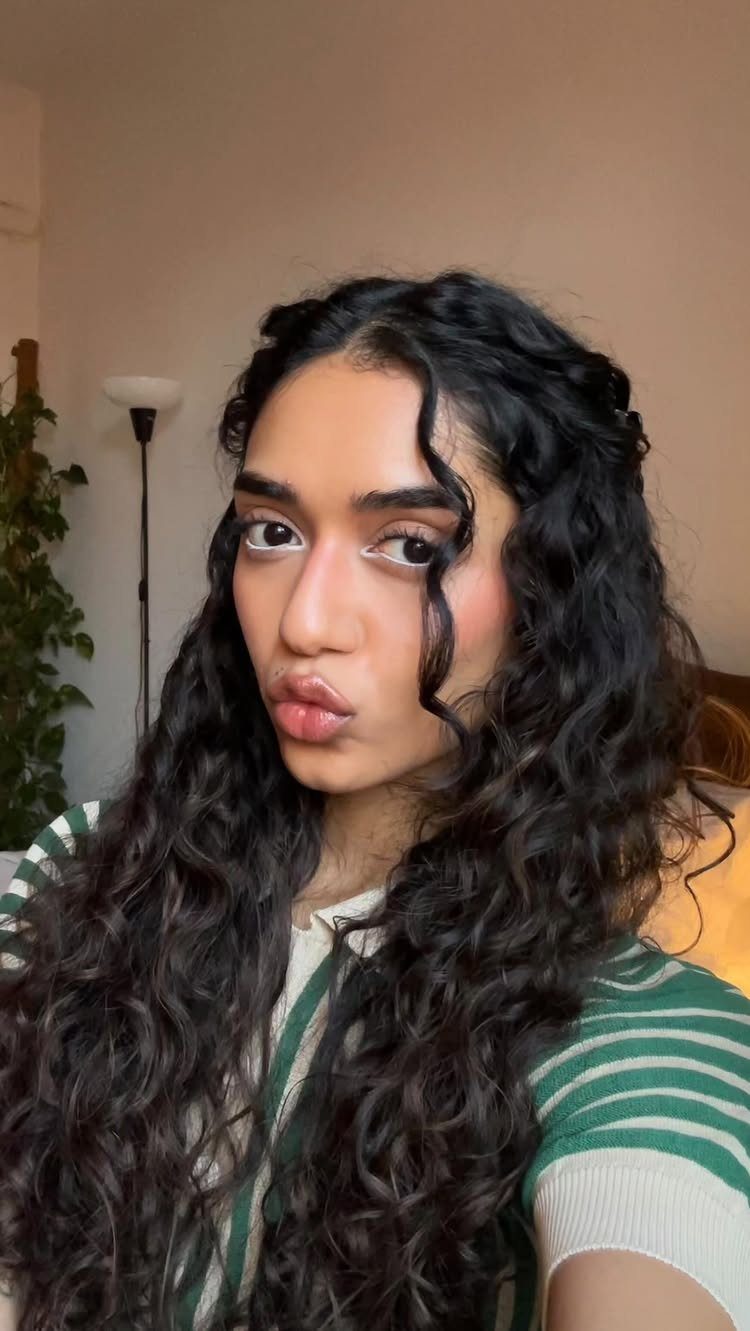 12 Good Hairstyles for Curly Hair, From Bangs to Braids 8 Woman with long dark curly hair and a middle part posing indoors.