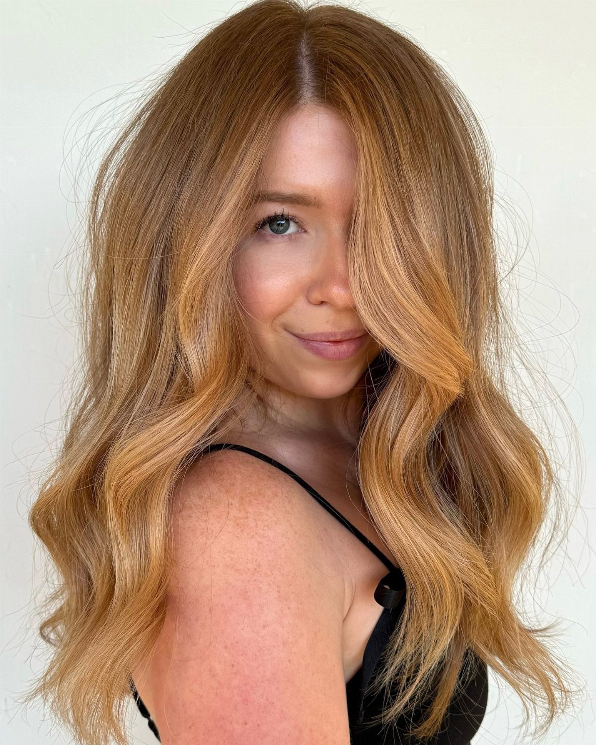 22 Hair Color Red and Blonde Ideas for Every Length 16 Woman with long wavy light red hair and golden blonde highlights posing.