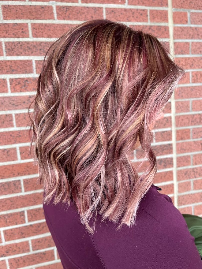 22 Hair Color Red and Blonde Ideas for Every Length 18 Short wavy hair with reddish-pink tones and blonde highlights against a brick wall.