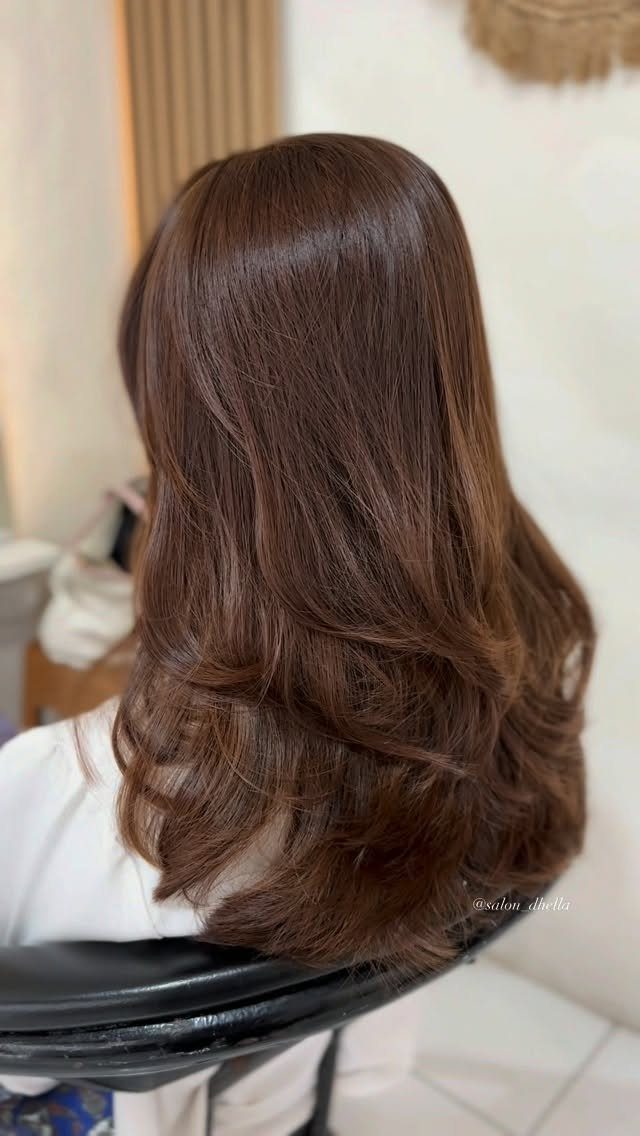 Hair Colour Ideas Brown: 13 Shades From Chestnut to Mahogany 1 Long wavy brown hair with warm chestnut tones styled in a salon chair