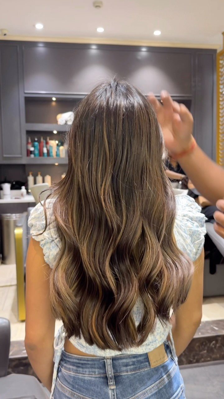 Hair Colour Ideas Brown: 13 Shades From Chestnut to Mahogany 3 Woman with long wavy brown hair and caramel highlights in a salon