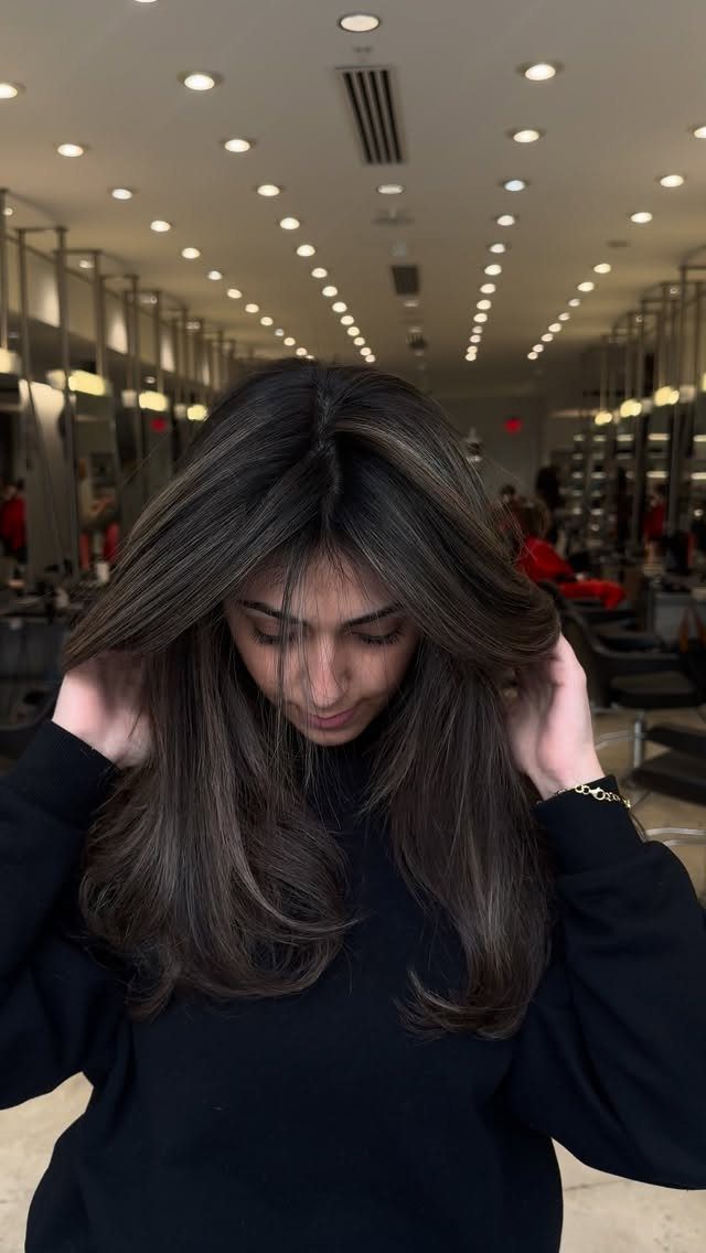 Hair Colour Ideas Brown: 13 Shades From Chestnut to Mahogany 10 Woman with long dark ash brown hair posing in a bright hair salon.