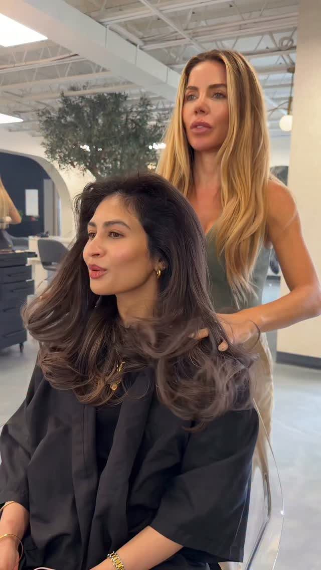 Hair Colour Ideas Brown: 13 Shades From Chestnut to Mahogany 8 Woman with voluminous light cocoa brown hair being styled in a modern salon.