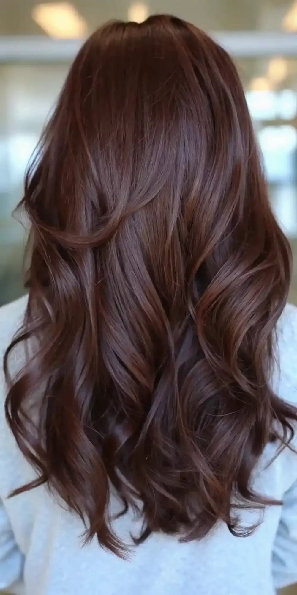 Hair Colour Ideas Brown: 13 Shades From Chestnut to Mahogany 11 Long wavy mahogany brown hair with a glossy finish seen from behind.