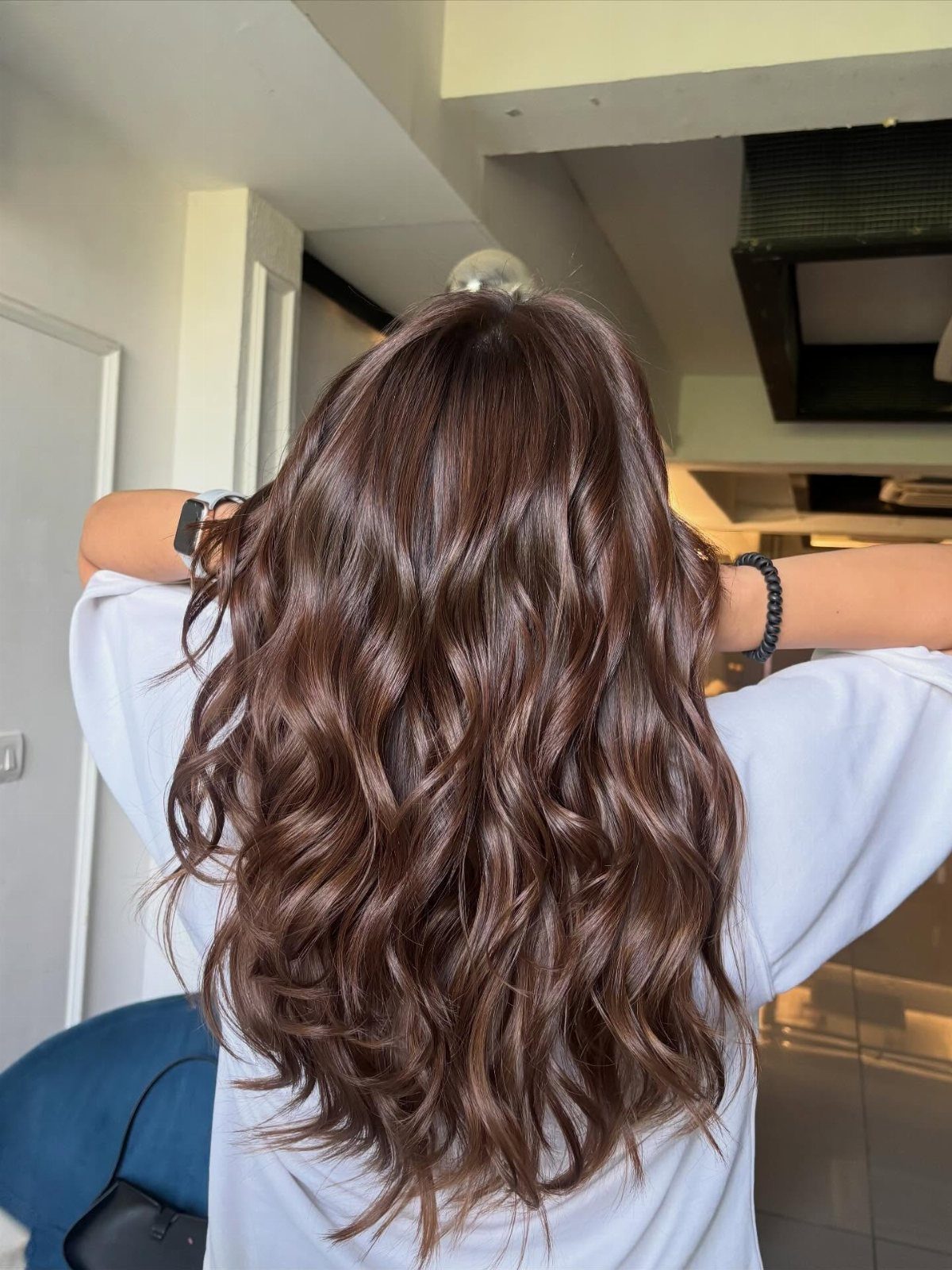 Hair Colour Ideas Brown: 13 Shades From Chestnut to Mahogany 2 Long wavy chocolate brown hair on a person wearing a white shirt.
