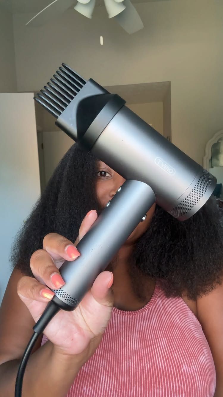 3 Hair Dryers for Natural Hair: Handheld, Diffuser, Brush 2 Person with curly natural hair holding a grey hair dryer with a diffuser attachment