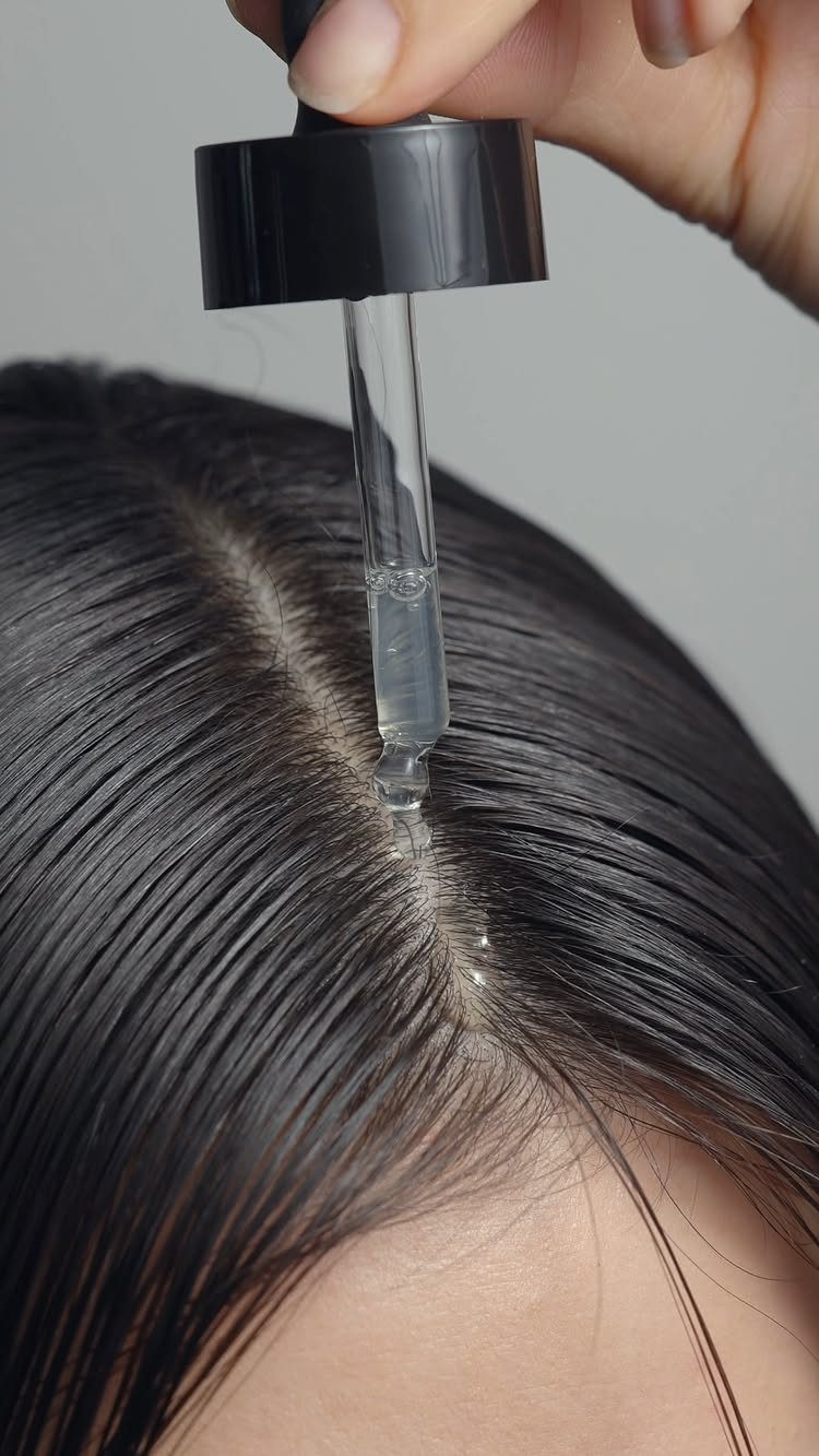 3 Hair Growth Tips at Home: Lemon, Rosemary, Serum 3 Glass dropper applying clear hair serum to the scalp of dark hair