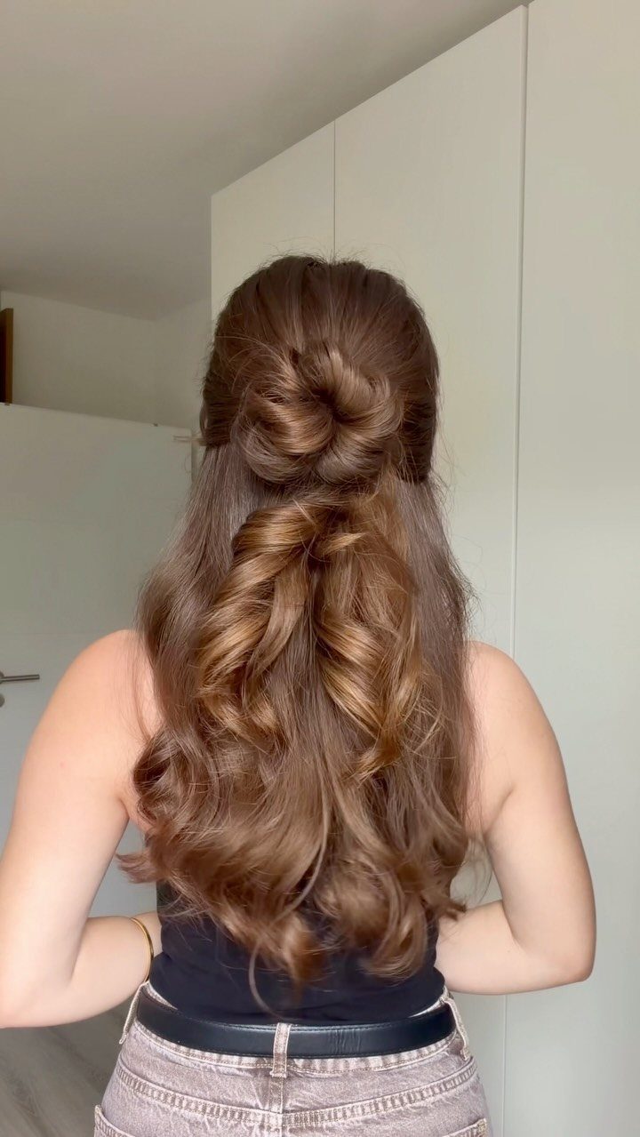 Woman with long brown wavy hair styled in a half-up twisted bun.