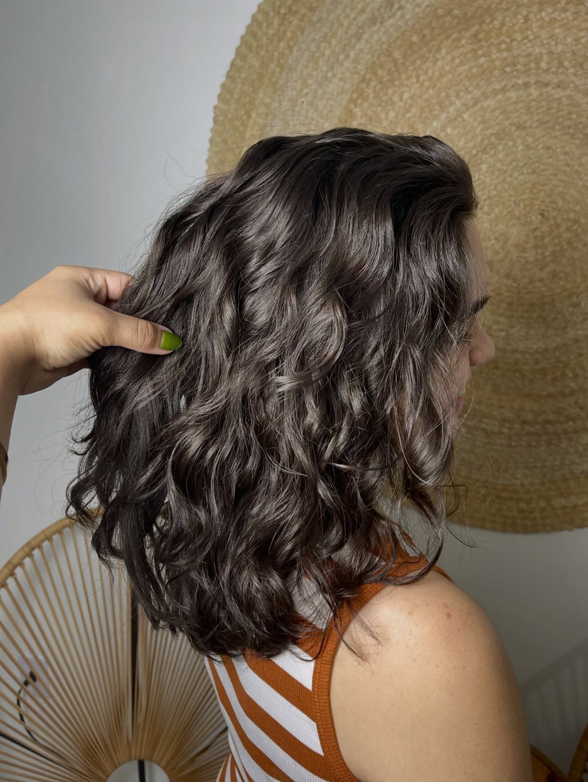 Woman with a dark brown wavy lob haircut and orange striped top.