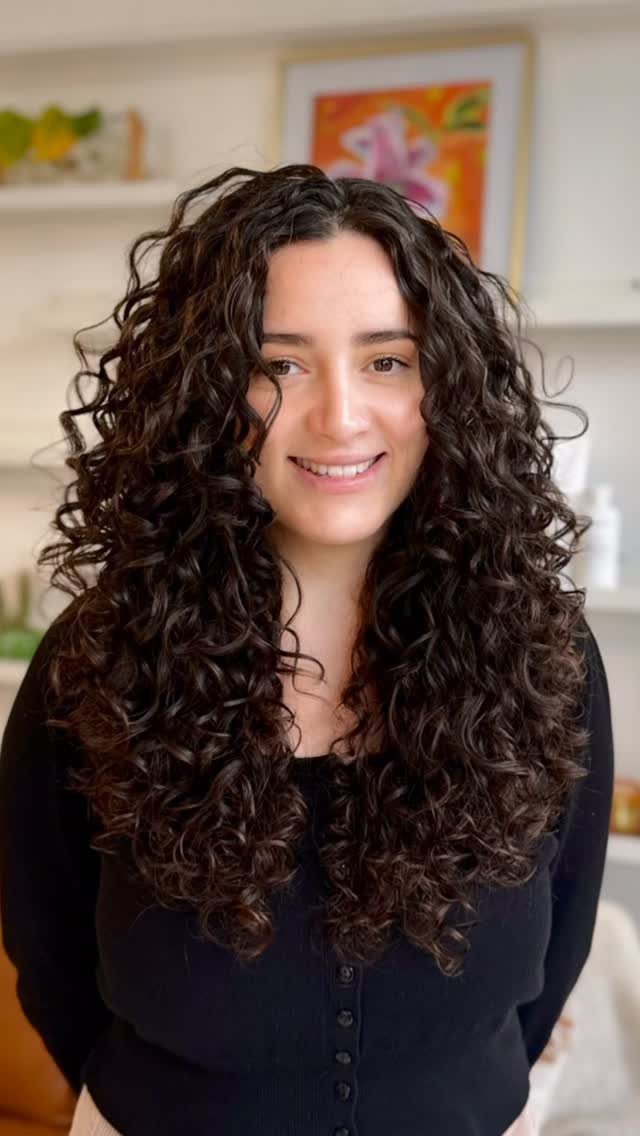 Woman with medium-length dark brown hair styled in defined spiral curls and ringlets.