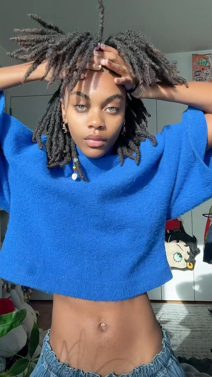 15 Ways to Pick a Hairstyle for Sweater Weather 15 Woman with dark dreadlocks wearing a bright blue cropped sweater and blue jeans.