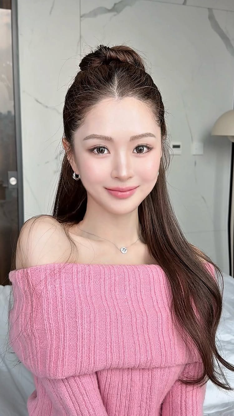 15 Ways to Pick a Hairstyle for Sweater Weather 5 Woman with long brown hair in a half-up bun wearing a pink sweater