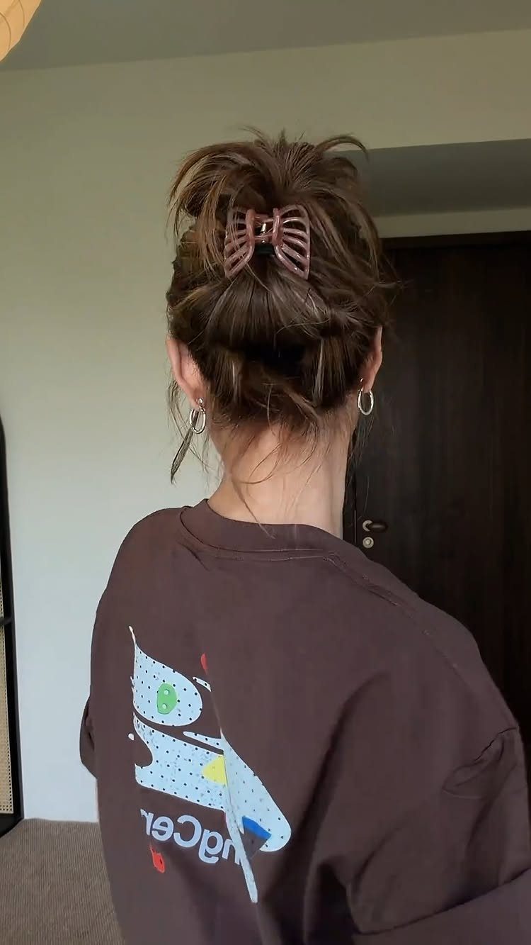 15 Ways to Pick a Hairstyle for Sweater Weather 4 High messy bun secured with a brown claw clip on a person's head.