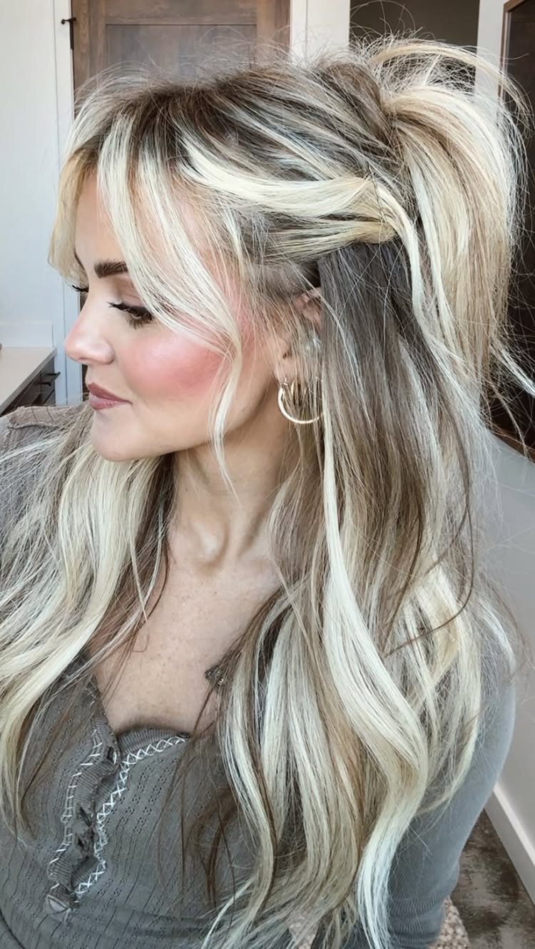 15 Ways to Pick a Hairstyle for Sweater Weather 10 Woman with voluminous blonde highlighted hair in a half-up ponytail and loose waves.