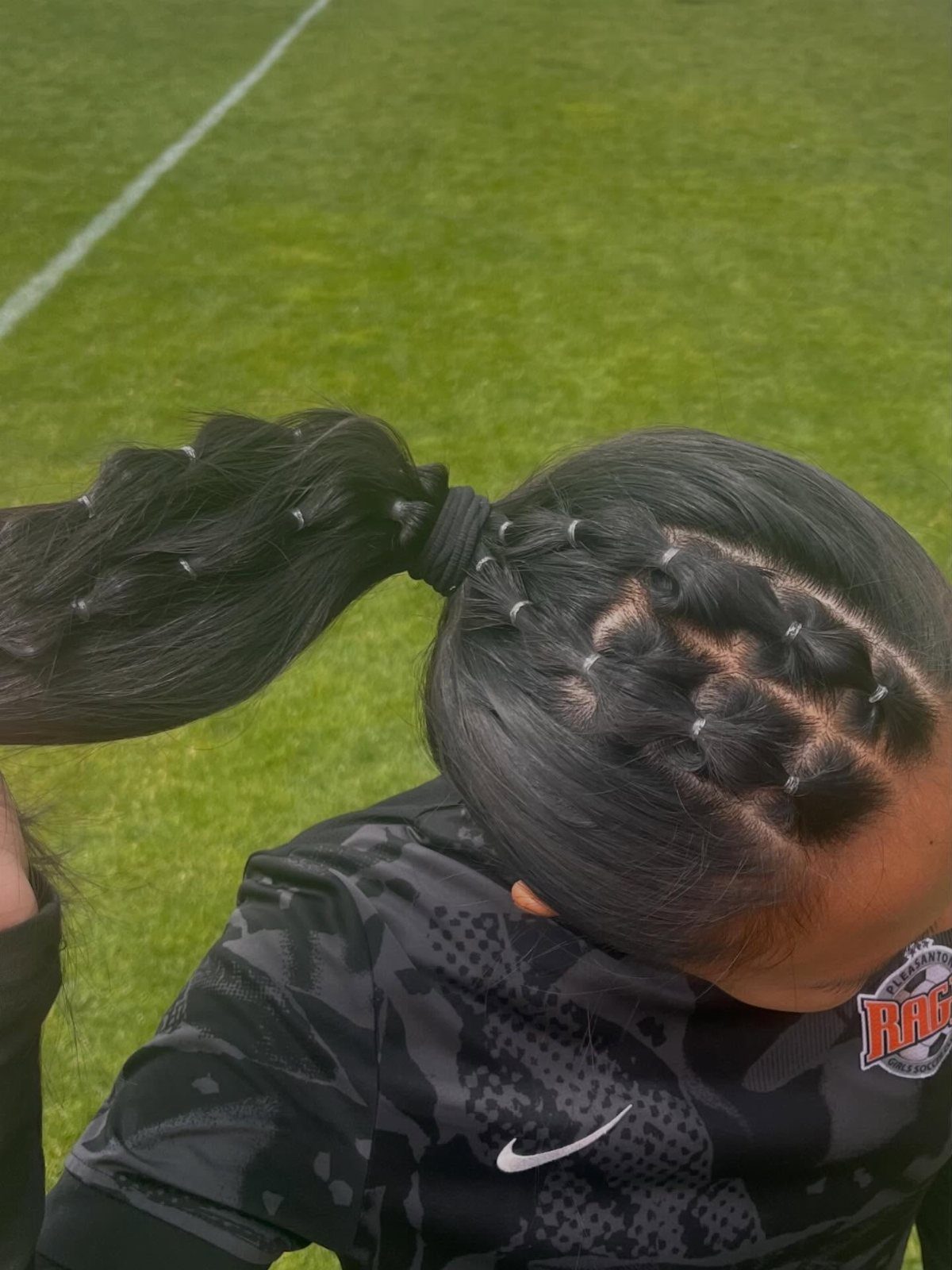 17 Hairstyles for Football Games: Braids, Buns & Ponytails 1 High bubble ponytail with small scalp braids on a person in athletic gear.