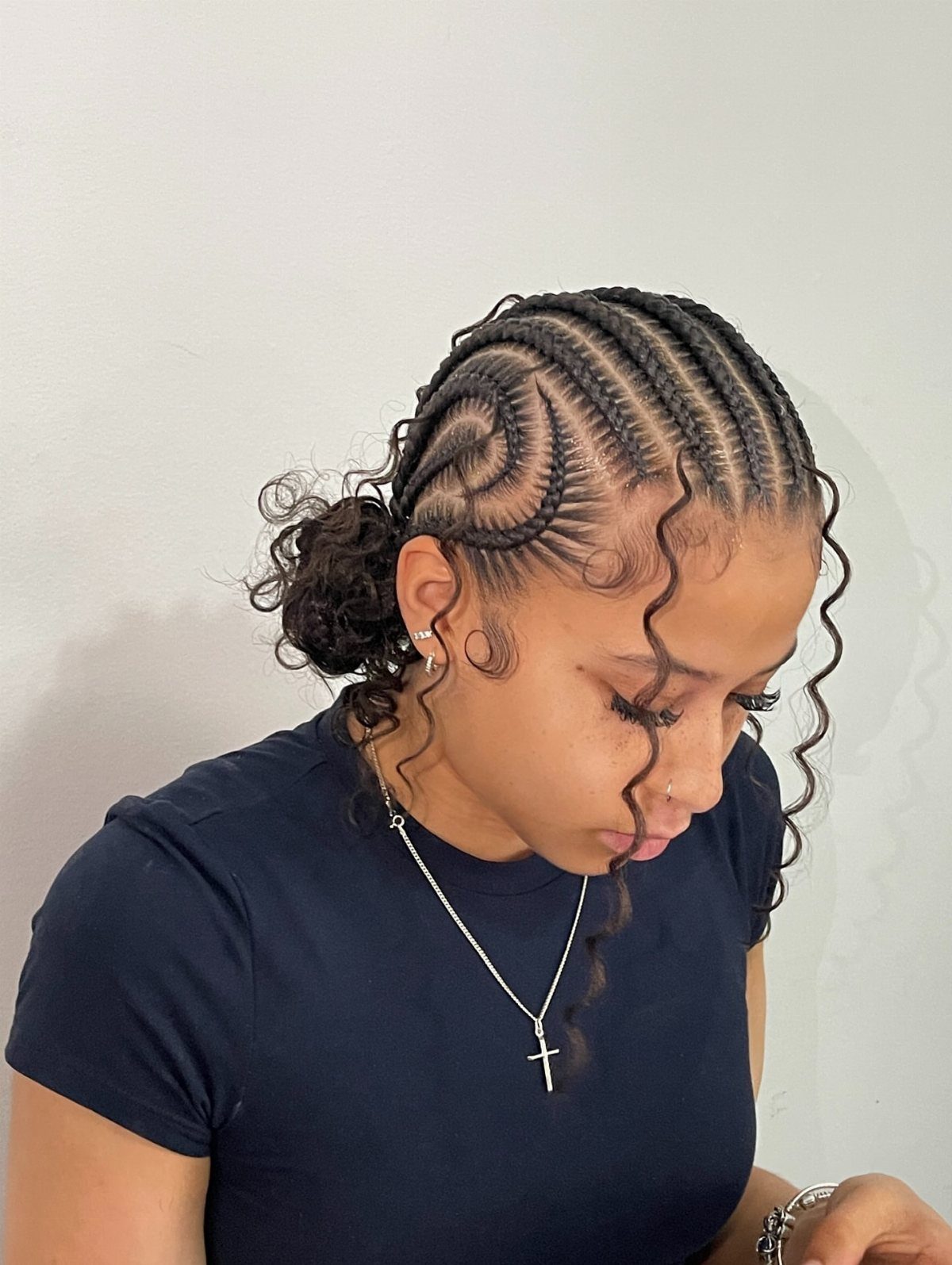 17 Hairstyles for Football Games: Braids, Buns & Ponytails 8 Woman with curved cornrow braids and a low curly bun wearing black shirt