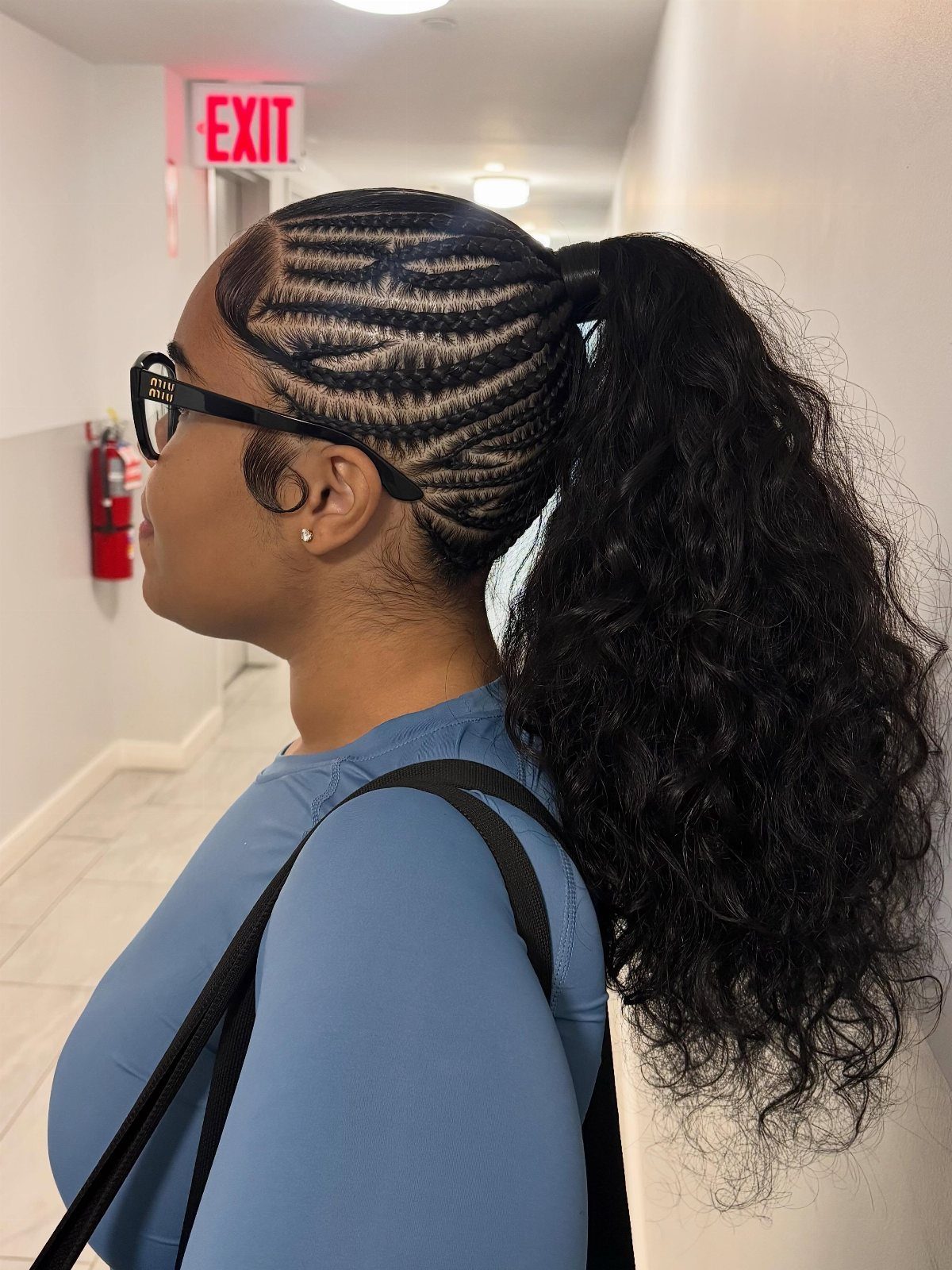 Woman with cornrow braids leading into a high, voluminous curly ponytail.