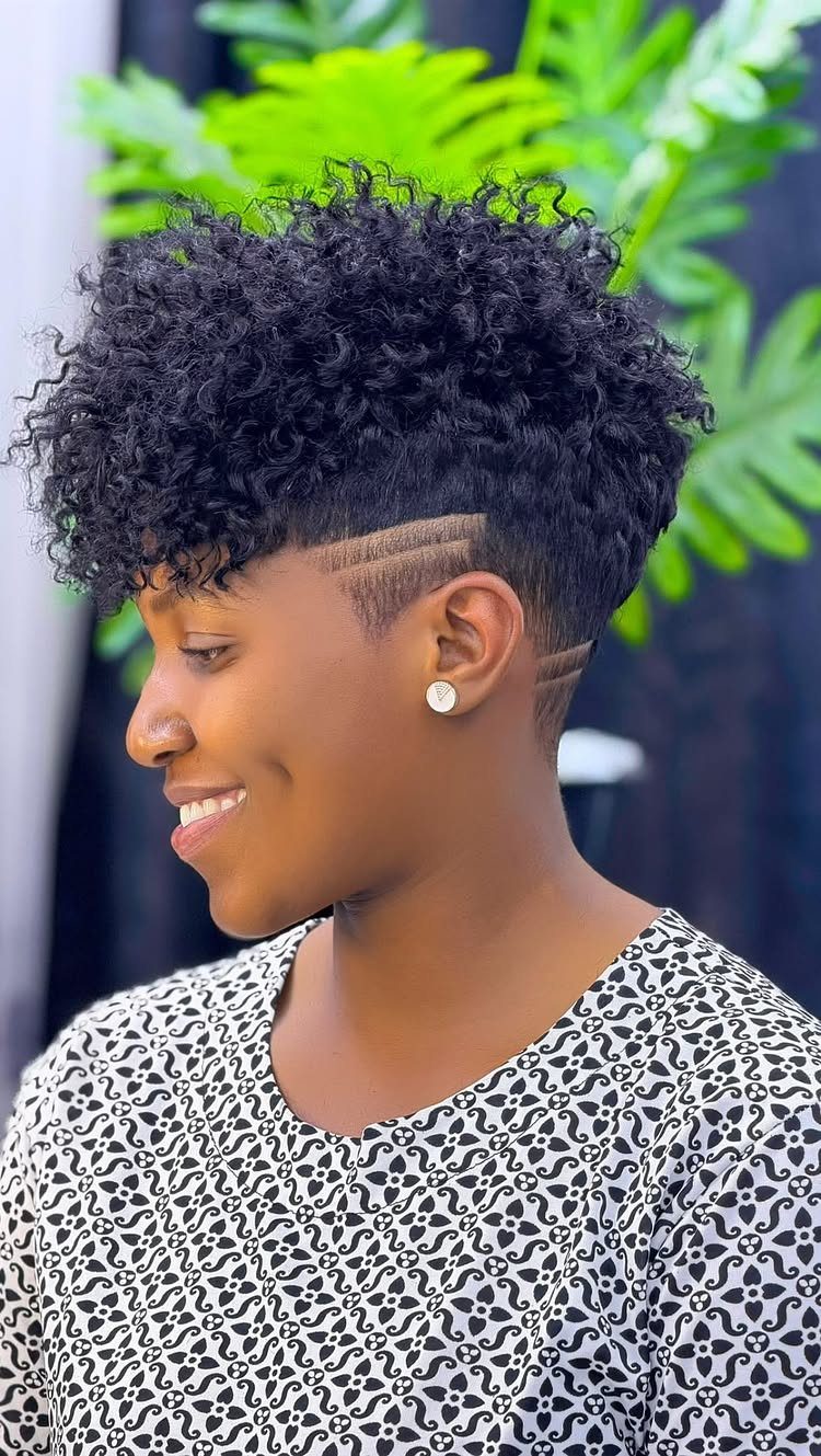 Woman with a curled mohawk hairstyle and tapered sides with etched hair designs.