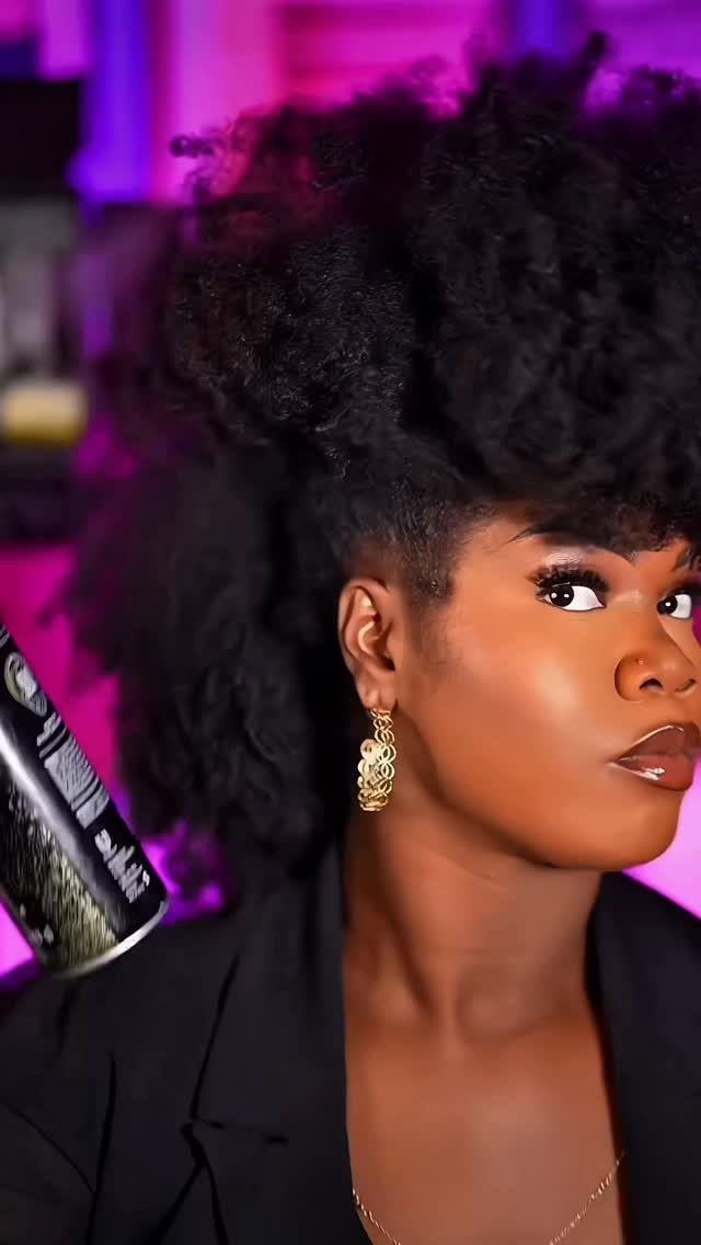Woman with a voluminous curly faux hawk hairstyle and gold earrings.