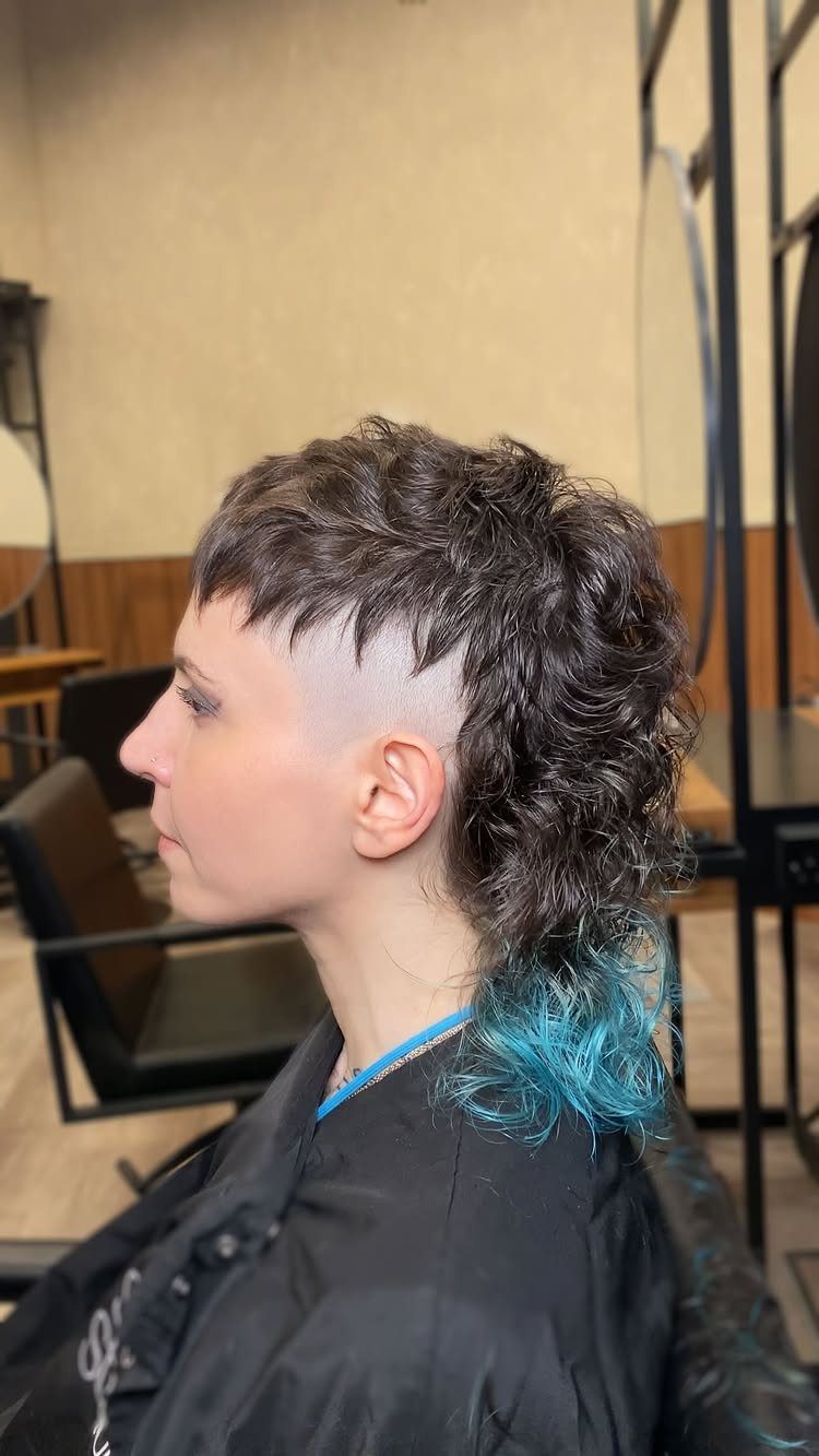 Person with brown curly fringe and shaved undercut with blue dyed ends.