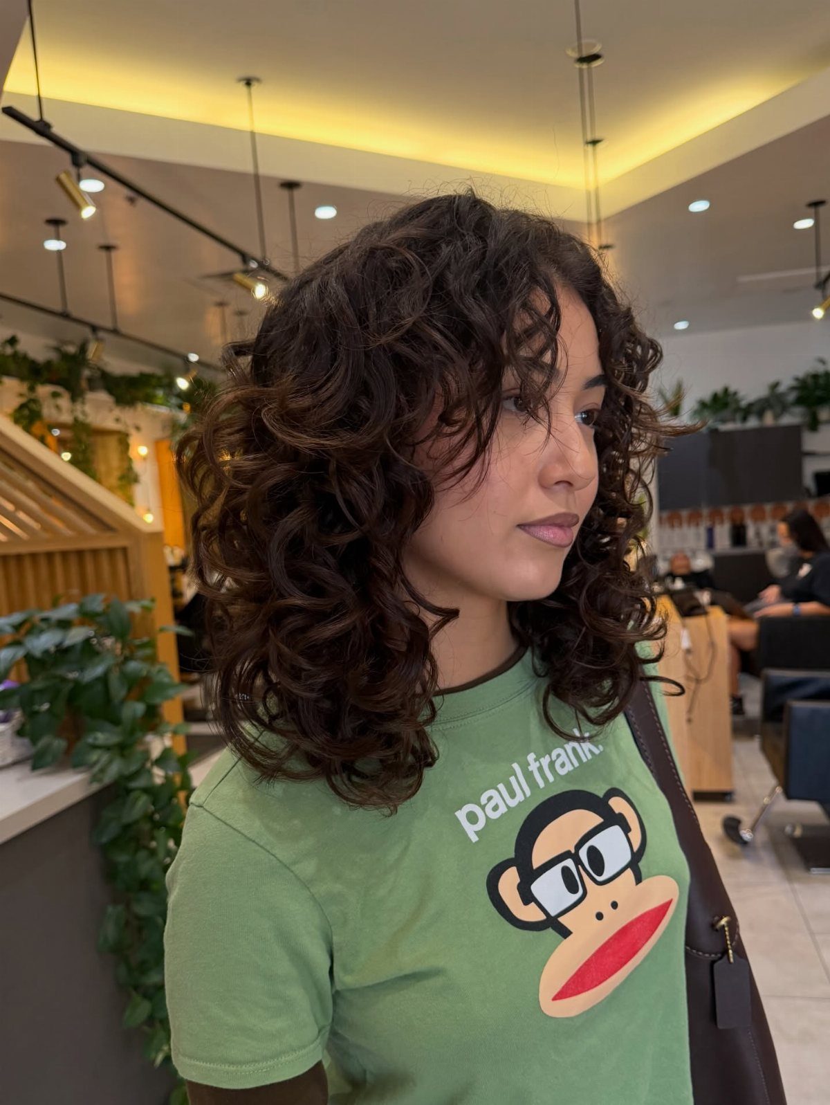 Woman with medium length dark brown curly layered hair in a hair salon