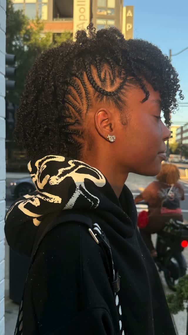 Person with curly hair and cornrow braids on the sides in profile view.