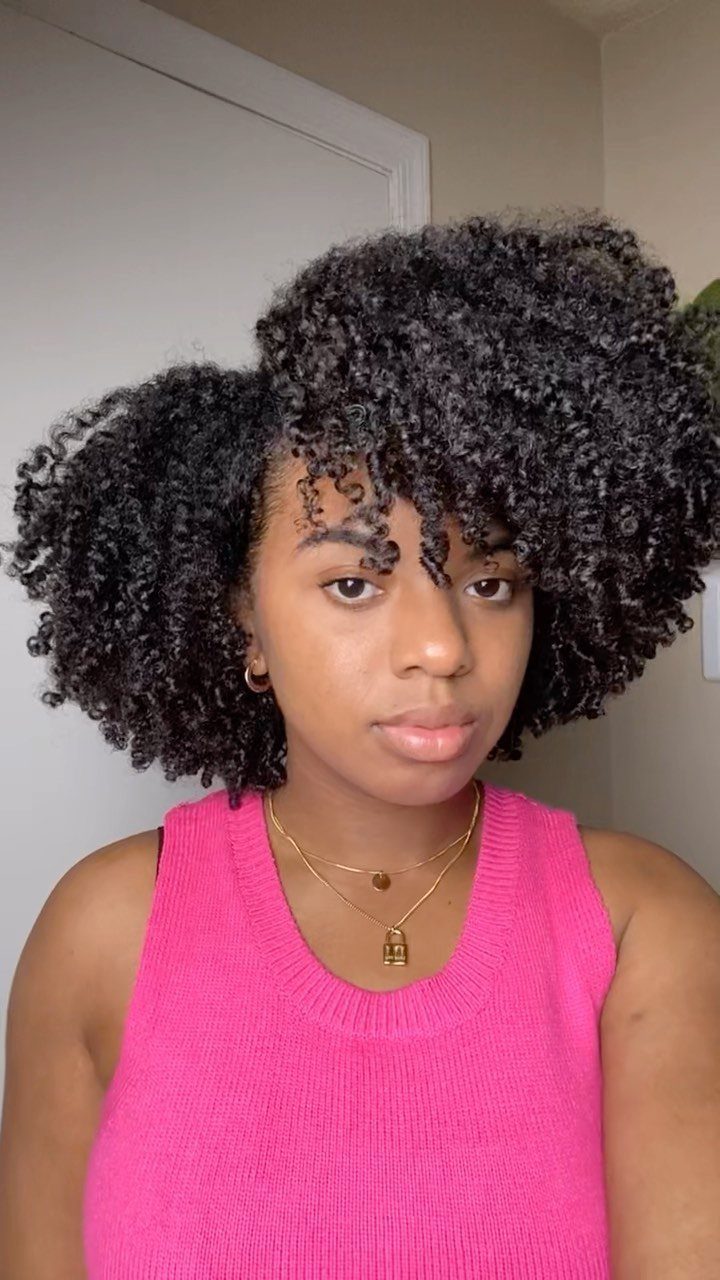 Woman with voluminous dark curly hair styled in a deep side part.