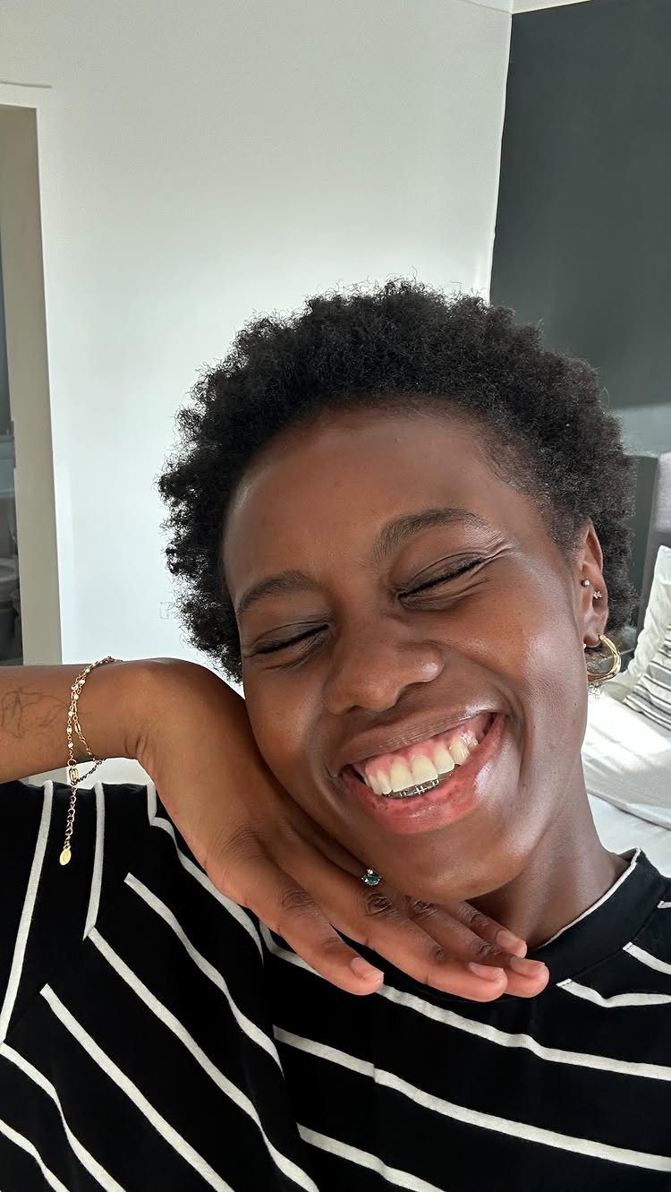 22 Hairstyles for Real Hair, from Bantu Knots to Bobs 4 Smiling woman with a short natural afro hairstyle wearing a striped shirt.