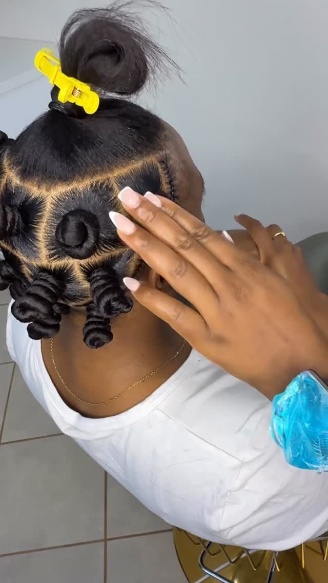 22 Hairstyles for Real Hair, from Bantu Knots to Bobs 1 Dark hair styled in coiled Bantu knots with a yellow hair clip.