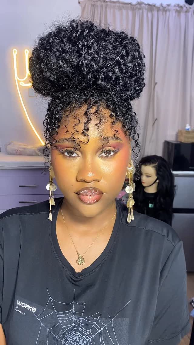 22 Hairstyles for Real Hair, from Bantu Knots to Bobs 20 Woman with curly dark hair styled in a high voluminous bun and tendrils