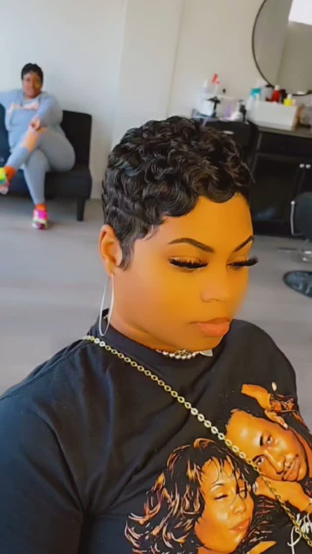 22 Hairstyles for Real Hair, from Bantu Knots to Bobs 14 Woman with a short curly black pixie cut wearing a black graphic t-shirt.