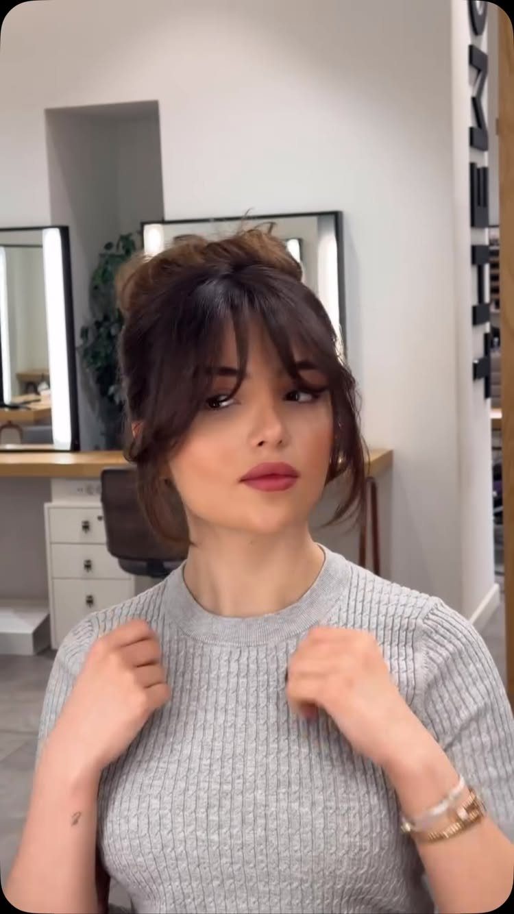 6 Hairstyles to Hide Bangs: Easy Ideas for Every Length 6 Woman with brown hair in a high bun and curtain bangs framing her face.