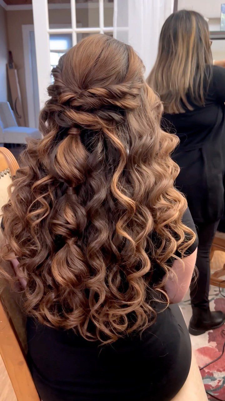 Long curly brown hair styled in a half-up half-down look with twists.