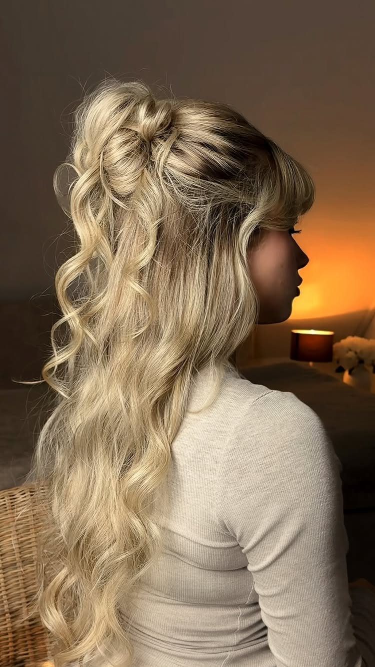 Blonde woman with a high curly ponytail and full fringe in profile.