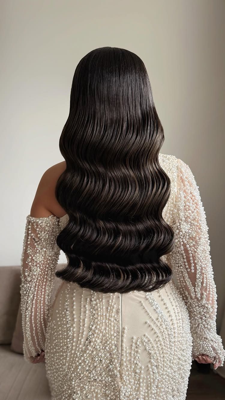 Long dark brown hair styled in glossy Hollywood waves and a pearl dress.