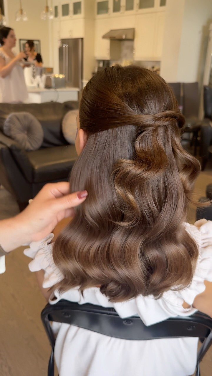 Woman with brown wavy hair styled in a knotted half-up wedding hairstyle.