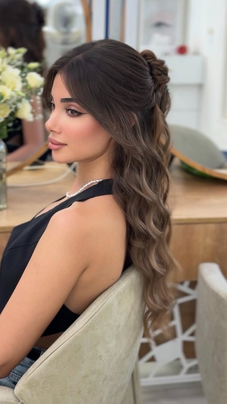 Woman with long brown wavy hair partially pinned back in a side twist.